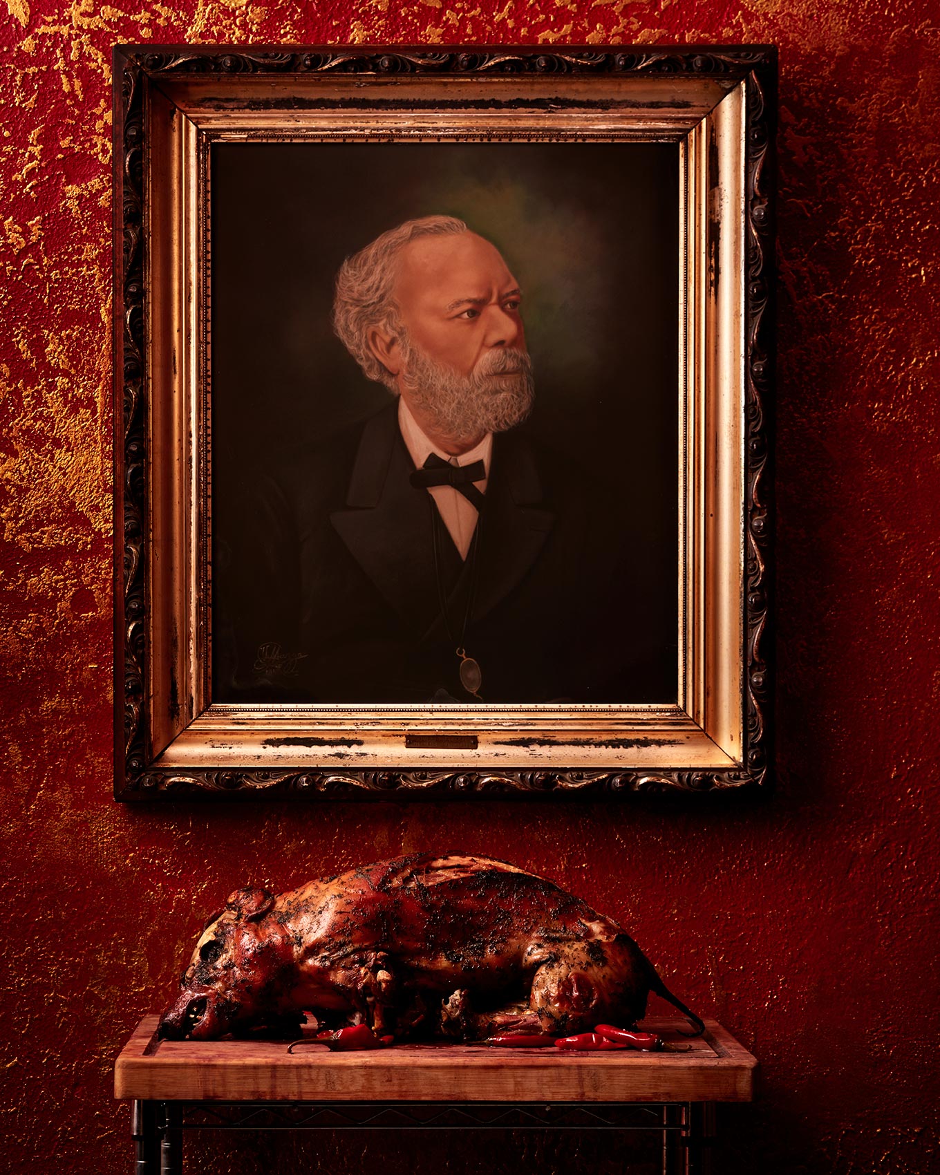 Whole roasted pig placed under a portrait at a restaurant in South Philadelphia.