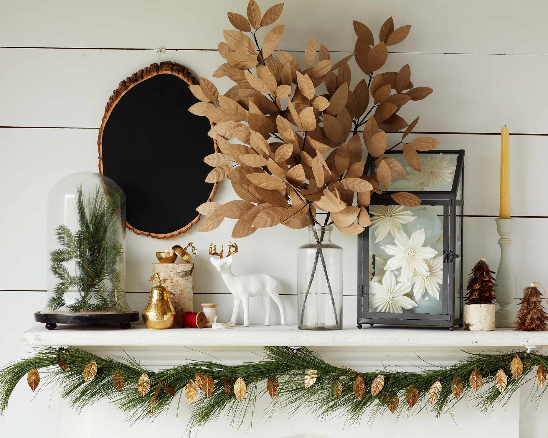 Christmas mantle with various Holiday props and dried leaves.
